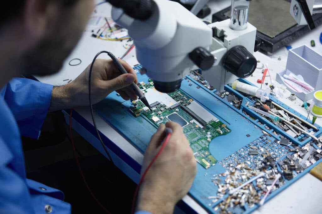 Técnico reparando placa madre de laptop en taller de Huamachuco